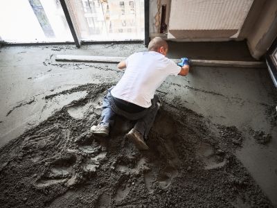 Eine Person gl&auml;ttet frischen Betonboden &ndash; zeigt Arbeitsschritte beim fachgerechten Einbau und Ausgleich von B&ouml;den