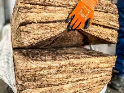 D&auml;mmmaterial wird von behandschuhten H&auml;nden verarbeitet &ndash; zeigt W&auml;rmed&auml;mmung zur Energieeinsparung im Bau