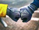 Zwei Personen mit Handschuhen sto&szlig;en F&auml;uste zusammen, symbolisieren Teamgeist, Begr&uuml;&szlig;ung oder Zusammenarbeit
