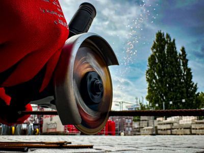Winkelschleifer schneidet Metallst&auml;be, Funken fliegen, zeigt Einsatz von Maschinen im Bauhandwerk drau&szlig;en