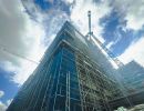 Gro&szlig;e Baustelle mit Ger&uuml;sten und Kran, Hochhaus im Rohbau, Betonstruktur und Baufortschritt deutlich erkennbar